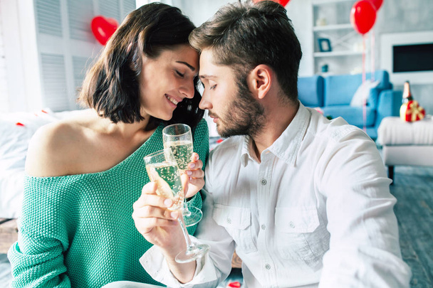 Young man and woman drinking champagne at bedroom - Фото, изображение