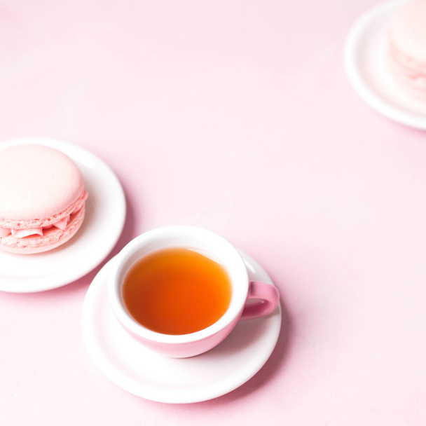 cup of tea served with fresh strawberry macaroons on pink pastel background - Foto, Imagem