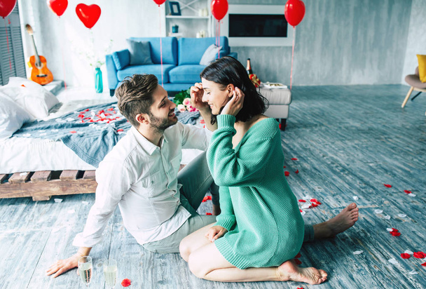 Young couple smiling and looking at each other on floor in bedroom - Фото, зображення