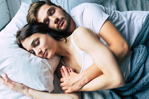 Young heterosexual couple cuddling on bed - Foto, afbeelding