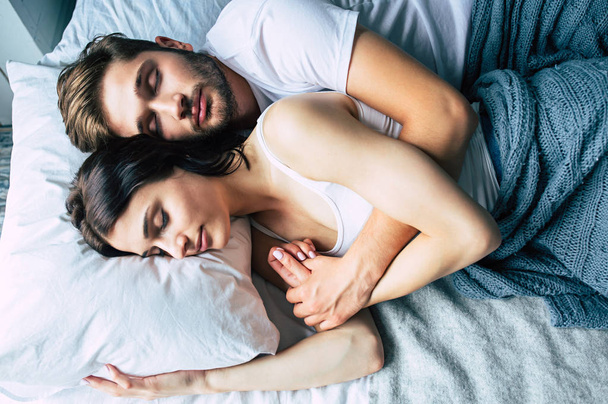 Young heterosexual couple cuddling on bed - Фото, зображення
