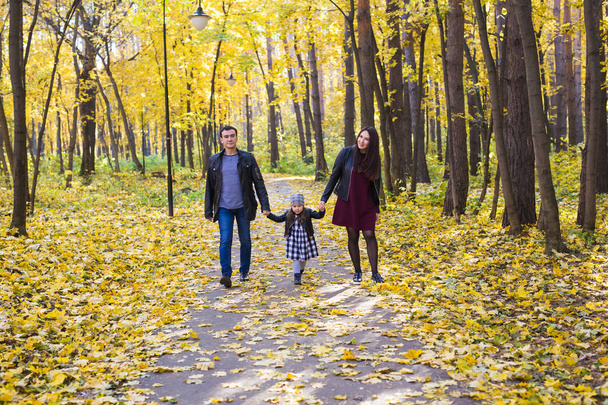 Familie, vallen, mensen concept - gemengd ras jonge gezin wandelen in het park op in herfstdag - Foto, afbeelding