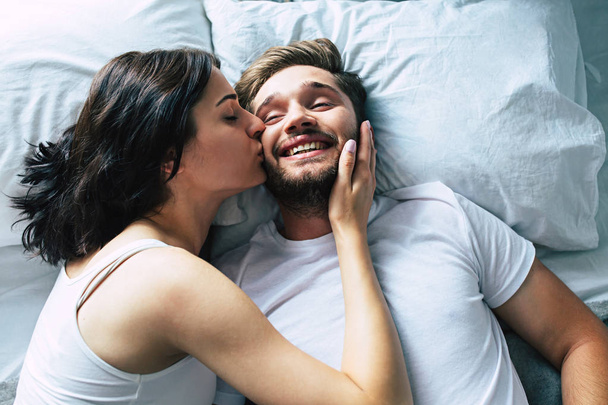 Young heterosexual couple cuddling on bed - Fotó, kép