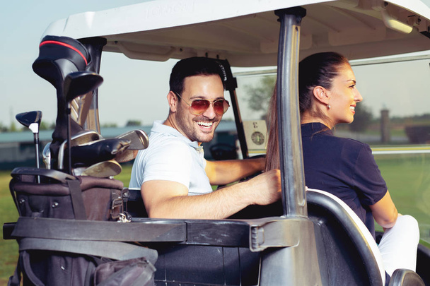 Paar glimlachend en rijden in buggy in de golf course - Foto, afbeelding