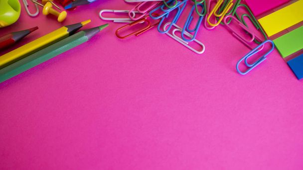 Bleistifte und Büroklammern auf dem Tisch. Schulbedarf auf rosa Hintergrund. Blick von oben mit Kopierraum - Foto, Bild