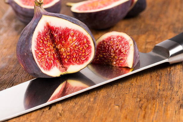 Group of sliced ripe, delicious and sweets figs with a kitchen knife on a old rustic wooden cutting board - Foto, Imagen
