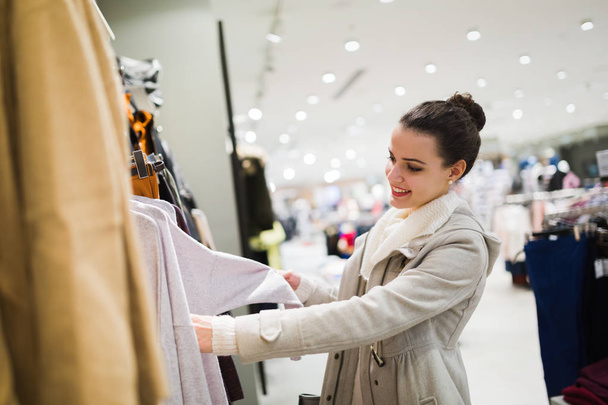 Young attractive woman buying clothes in shopping mall - Foto, Imagem