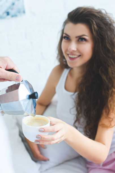 partial view of man pouring coffee to beautiful smiling woman in bedroom  - Foto, afbeelding