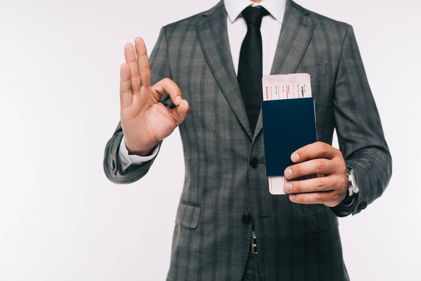 imagem cortada de empresário segurando passaporte e bilhete e mostrando gesto ok isolado no branco
 - Foto, Imagem