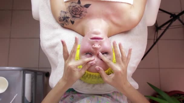Hands of professional masseuse massaging woman is face at beauty spa - Imágenes, Vídeo