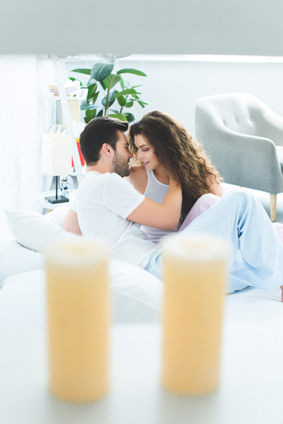 selective focus of smiling young couple able to kiss on bed - Foto, Imagen