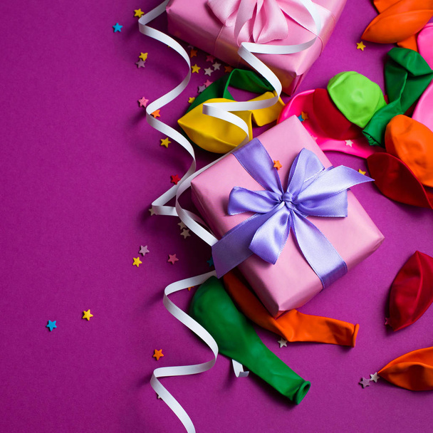 Feestelijke achtergrond van paarse materiële kleurrijke ballonnen slingers confetti vak cadeau. Top uitzicht plat lag kopie ruimte - Foto, afbeelding