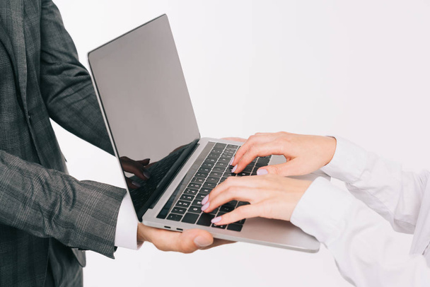 immagine ritagliata di uomo d'affari che tiene il computer portatile per donna d'affari isolata su bianco
 - Foto, immagini