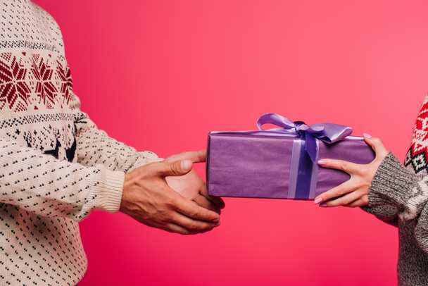 image recadrée de petite amie présentant cadeau au petit ami isolé sur rose
 - Photo, image