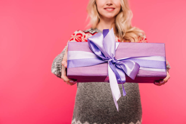 cropped image of girl in sweater showing violet present isolated on pink - Foto, imagen