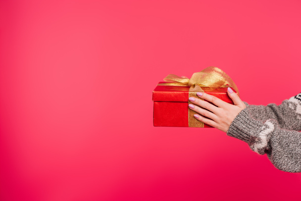 cropped image of girl in sweater holding gift box in hands isolated on pink - Foto, immagini