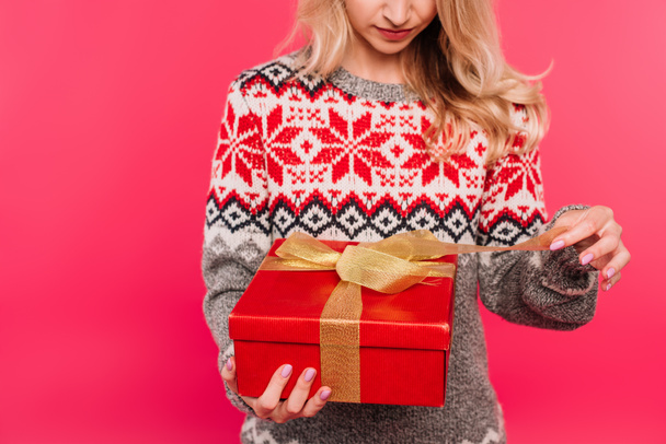 cropped image of girl in sweater opening present isolated on pink - Foto, imagen