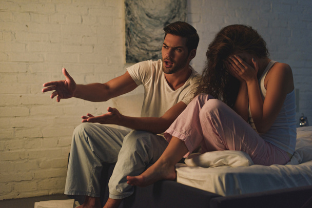 young couple in pajamas quarreling on bed, relationship difficulties concept  - Фото, изображение