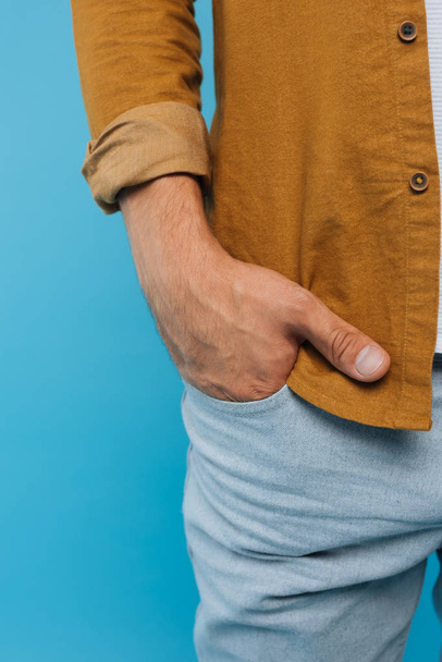 imagen recortada de hombre de pie con la mano en el bolsillo aislado en azul
  - Foto, imagen