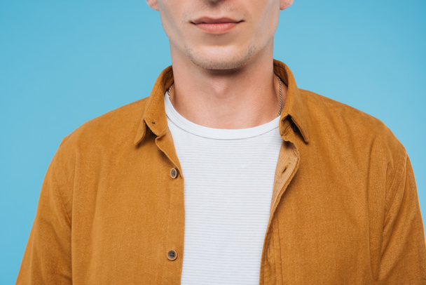 cropped image of man standing in brown shirt isolated on blue - Zdjęcie, obraz