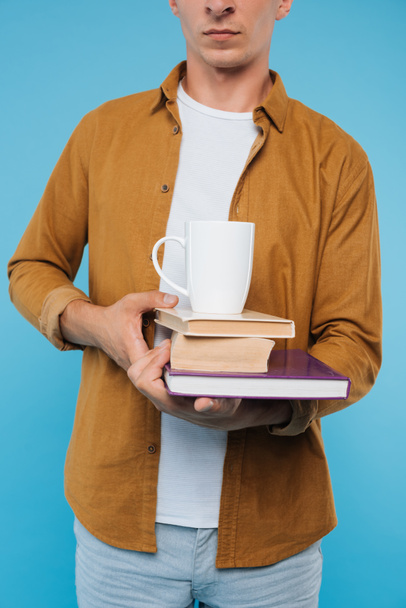 cropped image of man holding books and cup of coffee isolated on blue  - Photo, Image