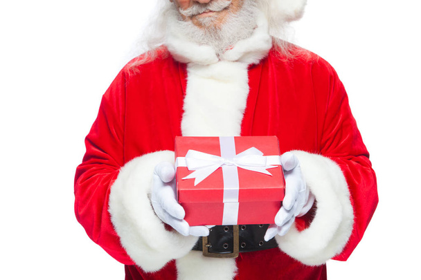 Christmas. Smiling Santa Claus in white gloves is holding a gift red box with a bow. Pointing at the gift. Isolated on white background. - Photo, Image