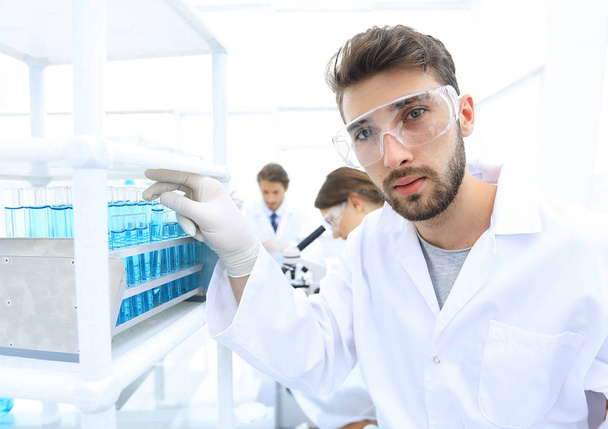 Joven científico masculino mirando una muestra en una competición de tubos de ensayo
 - Foto, imagen