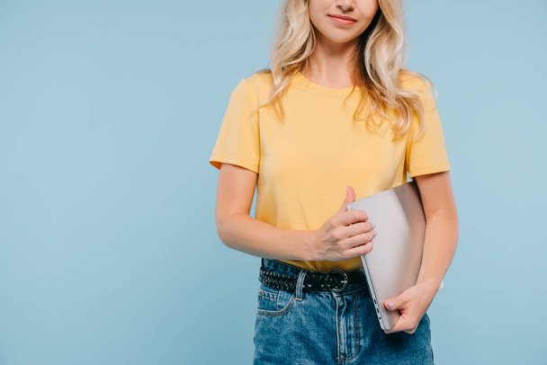 cropped image of girl in shirt and shorts standing with laptop isolated on blue - Foto, imagen