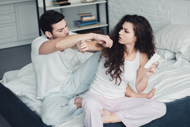 high angle view of young couple quarreling in bedroom, girl holding smartphone - Photo, Image