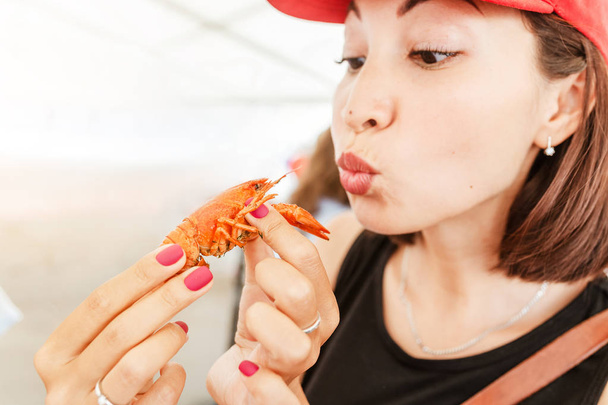 Mujer joven comiendo rojo hervido delicioso cangrejo de río o langosta de río cangrejo. Cocina local y concepto de mariscos
 - Foto, Imagen
