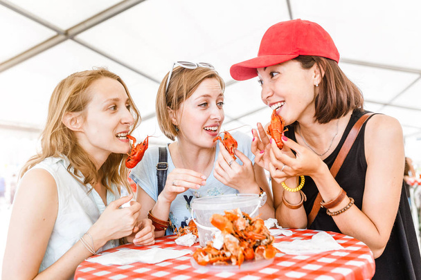 Skupina mladých mnohonárodnostní přátel dívka jíst kraby, mořské plody nebo Rak venkovní restaurace - Fotografie, Obrázek
