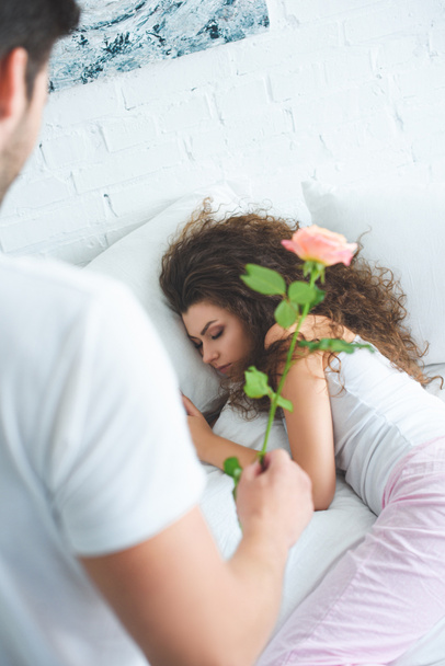 jonge man die presenteert roze bloem aan mooie slapende meisje  - Foto, afbeelding
