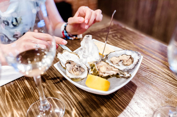 Frau isst Austern und Schalentiere im Restaurant. köstliche und delikate Meeresfrüchte-Küche - Foto, Bild