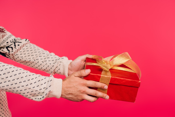 cropped image of man in sweater giving present isolated on pink - 写真・画像
