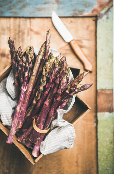 Fresh raw uncooked purple asparagus over rustic wooden tray background - Foto, Imagen