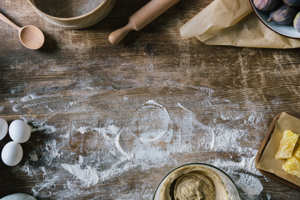 felülnézet rendetlen rusztikus, fából készült asztal kiömlött liszt és sütés összetevőkkel - Fotó, kép