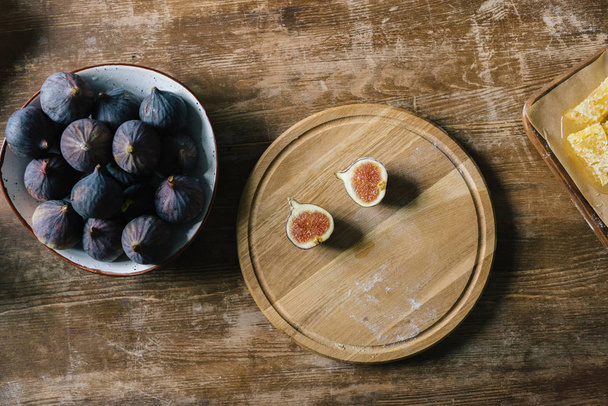 halves of fig on cutting board and pile in bowl on rustic wooden table - Foto, immagini
