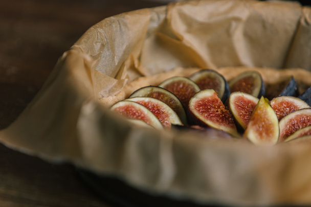 sliced figs in baking tray with parchment paper on rustic wooden table - Photo, Image