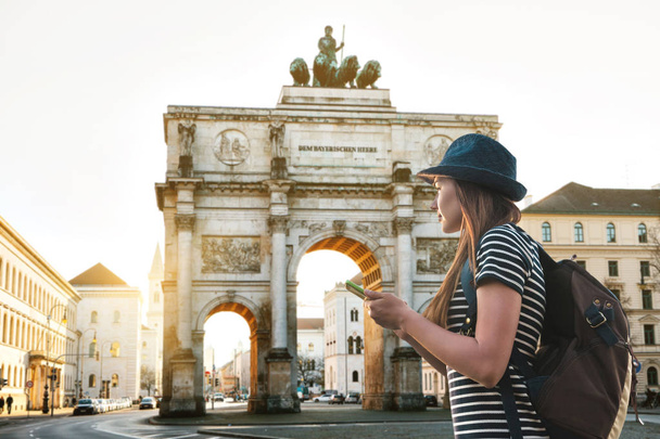 Туристическая девушка с рюкзаком смотрит достопримечательности Мюнхена в Германии
. - Фото, изображение