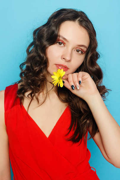 Beautiful brunette girl with green eyes make up and fresh skin posing at blue background with flower, skin care concept, beauty spa, bio product. Horizontal - Foto, Imagem