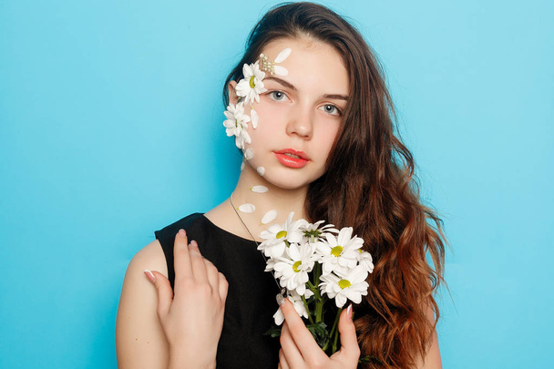 Beautiful brunette girl with green eyes make up and fresh skin posing at red background with flower, skin care concept, beauty spa, bio product. Horizontal - Fotoğraf, Görsel