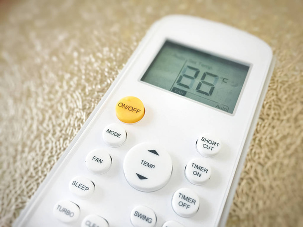 Exposição de um controle remoto do condicionador de ar com temperatura ajustada em 26 graus
 - Foto, Imagem