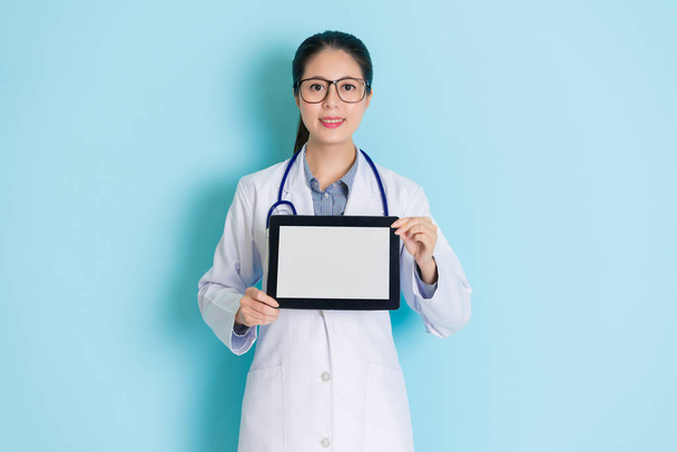pretty female medical holding a tablet in hands and smiling to show her friendly speciality. - 写真・画像