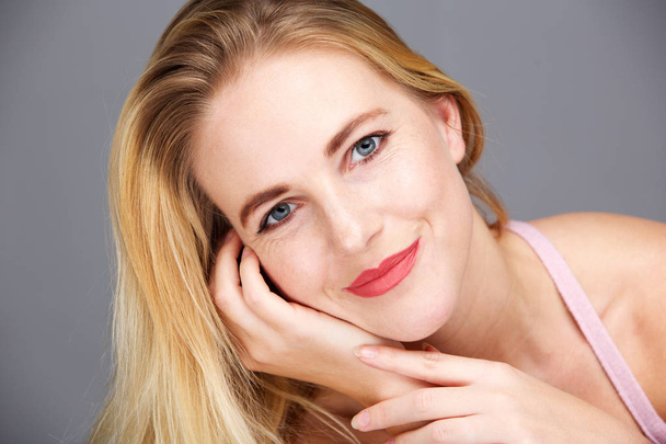 Nahaufnahme Schönheitsporträt einer glücklichen jungen blonden Frau vor grauem Hintergrund - Foto, Bild