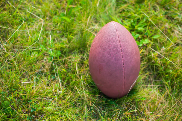 Bola para o futebol americano que coloca na grama verde
 - Foto, Imagem