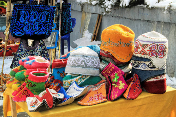 Various of Kazakh traditional souvenirs ethnic hats, shoes and horsewhip  with ornaments in market in Kok-tobe park, Almaty, Kazakhstan - Photo, Image