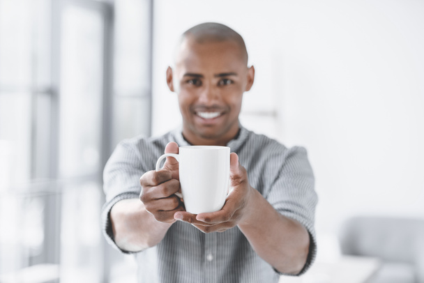 selective focus of african american businessman holding cup of coffee in hands - Foto, imagen