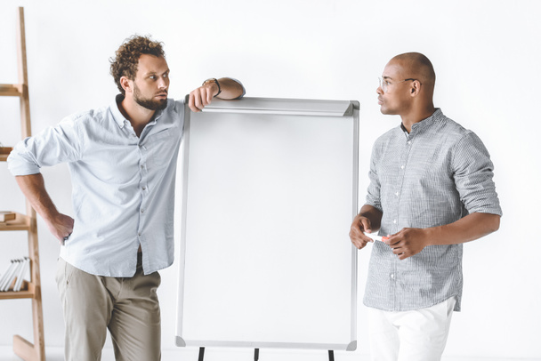 multi-etnische ondernemers permanent in de buurt van white-board tijdens zakelijke presentatie - Foto, afbeelding