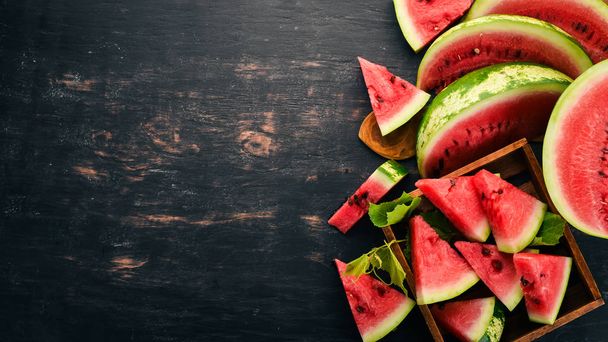 Watermelon in a wooden box. Sliced to pieces of watermelon. On a wooden background. Free space for text. Top view. - Photo, Image