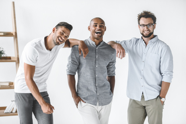 grupo multiétnico de jóvenes hombres de negocios sonrientes de pie en la oficina ligera
 - Foto, imagen
